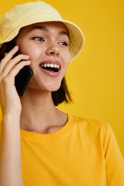 Belle fille dans un chapeau jaune style jeunesse casual parler au téléphone fond isolé