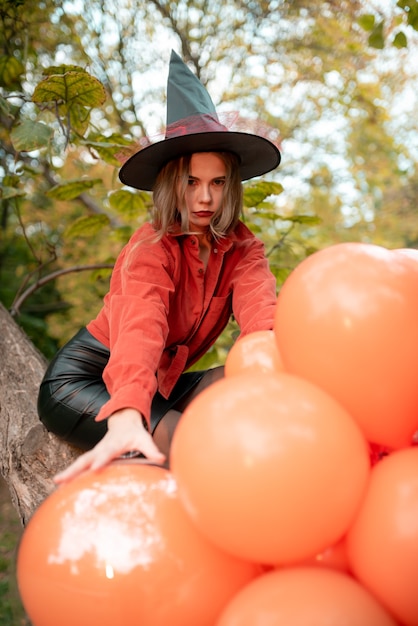 Belle fille dans une chemise orange, une jupe noire et un chapeau de sorcière. Regarde dans la caméra. Halloween