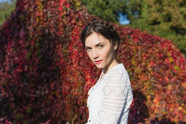 Belle fille dans un chemisier de dentelle blanche dans un parc en automne