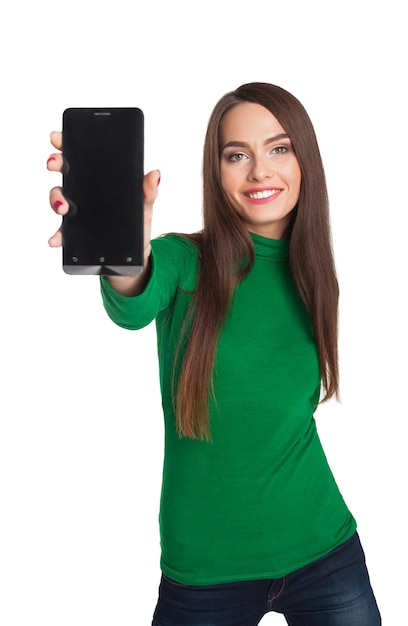 La belle fille dans un col roulé vert montre le téléphone