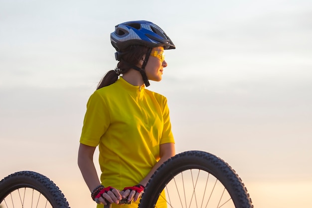 Belle fille dans un cycliste jaune sur un vélo atteint la lumière du soleil. Sports et loisirs. Nature et homme