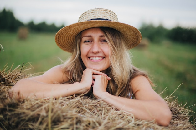 belle fille dans le domaine. femme et balles de foin. blonde dans un chapeau de paille. la vie au village