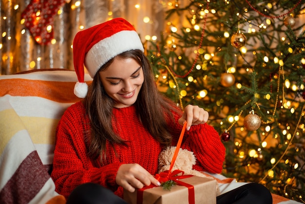 Belle fille dans un fauteuil ouvre la boîte-cadeau