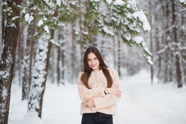 Belle fille dans la forêt enneigée d'hiver