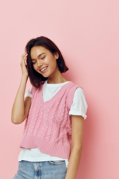 Belle fille dans un gilet rose posant des vêtements décontractés sur fond rose