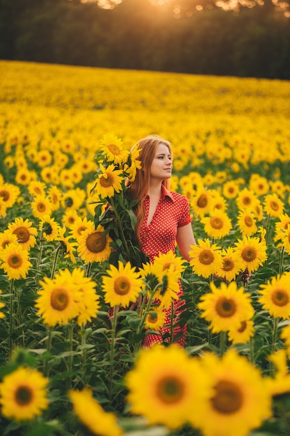 Belle fille dans un immense champ jaune de tournesols.