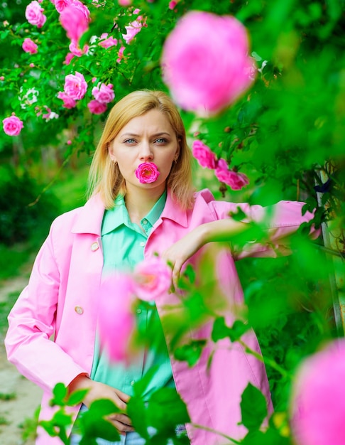 Belle fille dans le jardin fleuri. Femme sensuelle au parc avec des roses roses.