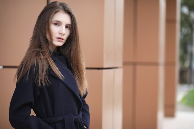 Belle fille dans un manteau dans le centre-ville d'affaires du nuageux