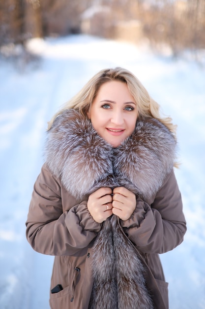 Belle fille dans un manteau de fourrure tenant au col