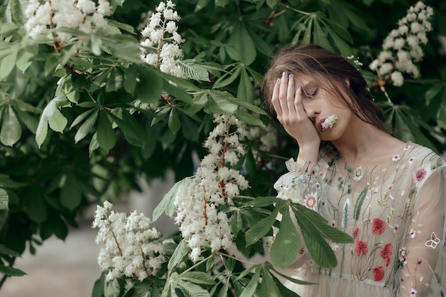 Belle fille dans une robe d'été posant sur un fond de fleurs