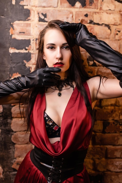 Belle fille dans une robe rouge posant l'image de vampire garde les mains près du visage mascarade de boîte de nuit concept Halloween
