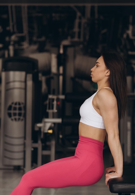 Une belle fille dans la salle de gym est assise sur un banc