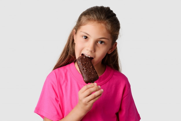 Belle fille dans un T-shirt rose, manger des glaces au chocolat