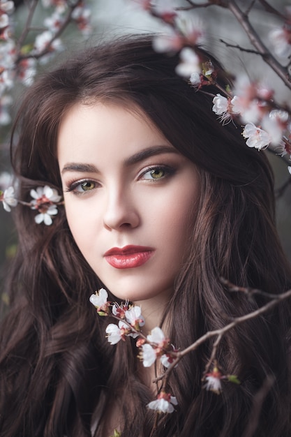 Belle fille debout à l'arbre en fleurs dans le jardin