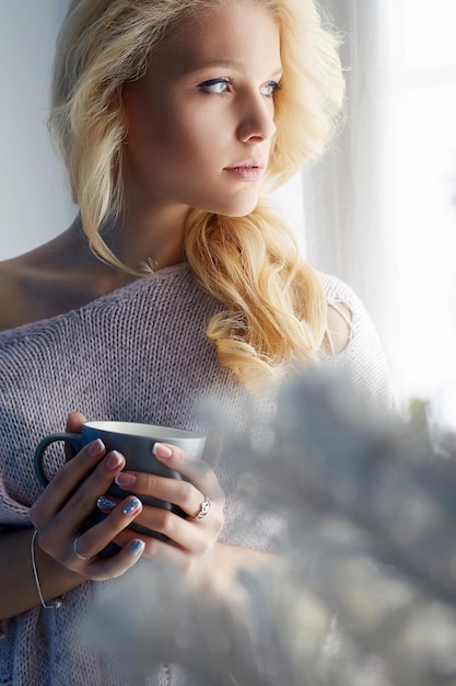 Belle fille debout à la maison avec une tasse de café