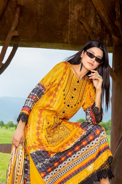 Belle fille debout sous une cabane avec une attitude portant une robe et des lunettes Desi