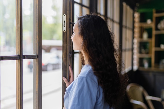 Photo belle fille devant une fenêtre un matin en ville