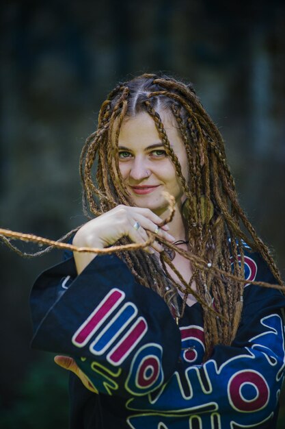 Belle fille avec des dreadlocks habillé style hippie pose à l'extérieur