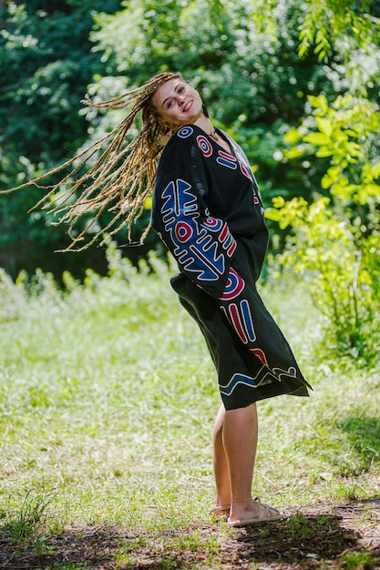 Belle fille avec des dreadlocks habillé style hippie pose à l'extérieur