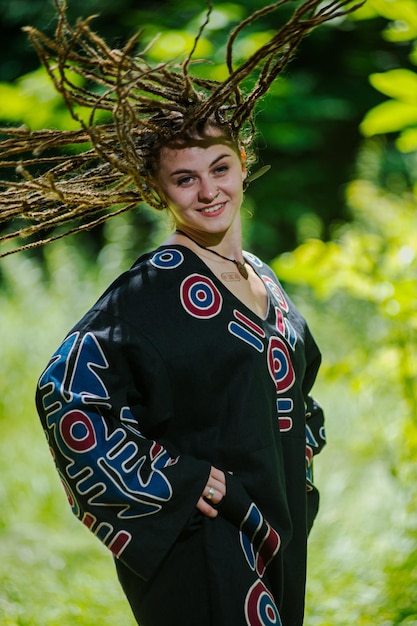 Belle fille avec des dreadlocks habillé style hippie pose à l'extérieur