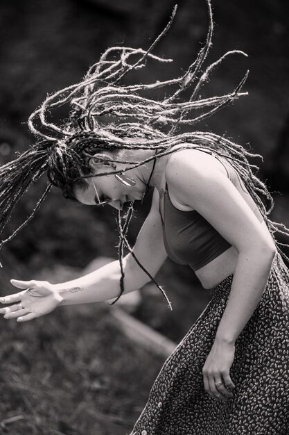 Belle fille avec des dreadlocks habillé style hippie pose à l'extérieur