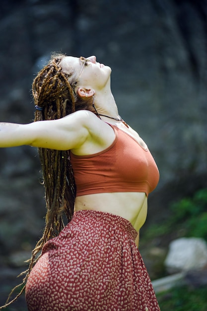 Belle fille avec des dreadlocks habillé style hippie pose à l'extérieur