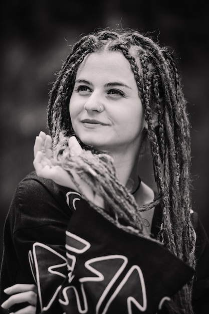 Belle fille avec des dreadlocks habillé style hippie pose à l'extérieur