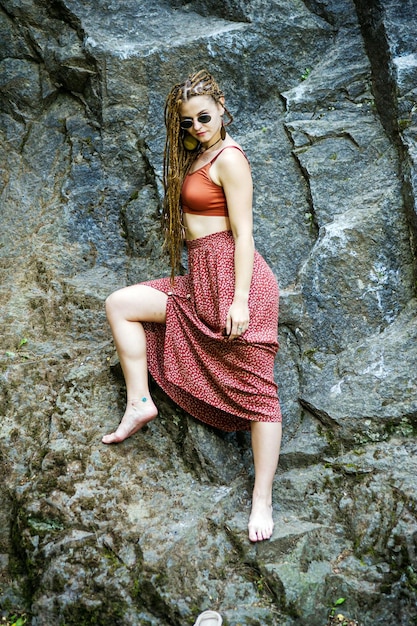 Belle fille avec des dreadlocks habillé style hippie pose à l'extérieur