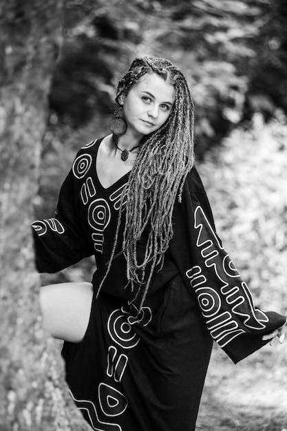 Belle fille avec des dreadlocks habillé style hippie pose à l'extérieur