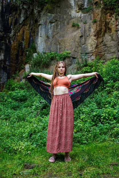 Belle fille avec des dreadlocks habillé style hippie pose à l'extérieur