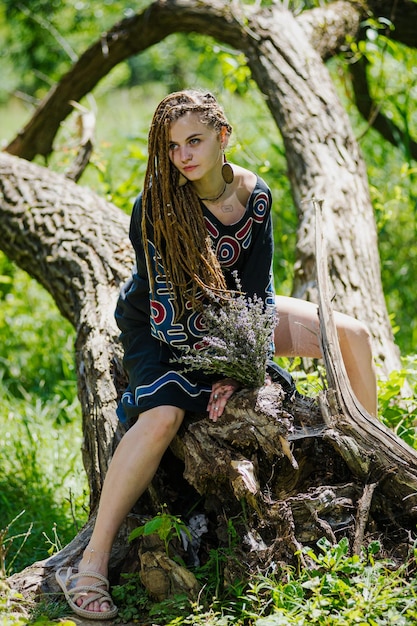 Belle fille avec des dreadlocks habillé style hippie pose à l'extérieur