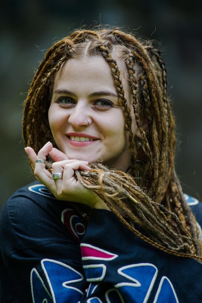 Belle fille avec des dreadlocks habillé style hippie pose à l'extérieur