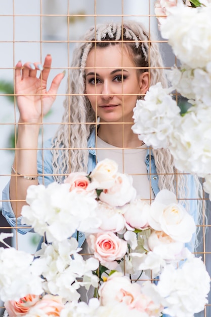 Belle fille avec des dreadlocks posant près d'un treillis décoré de fleurs