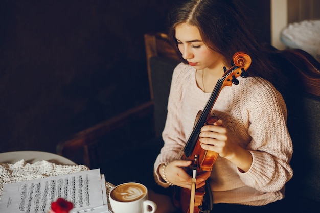 belle fille élégante, assis dans un café avec violon et boire du café