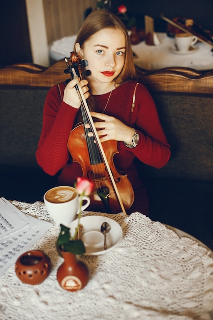 belle fille élégante, assis dans un café avec violon et boire du café