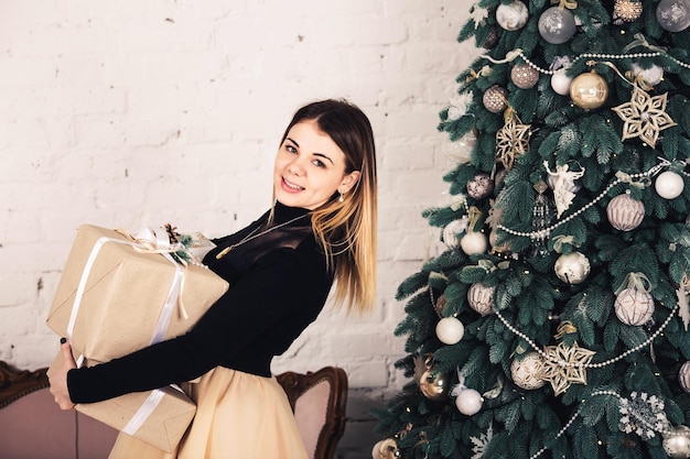 Belle fille élégante tenant le cadeau de Noël et souriant