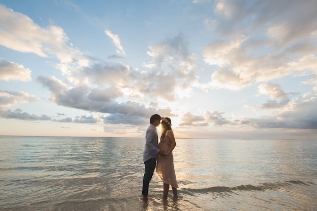 Belle fille enceinte et homme au coucher du soleil