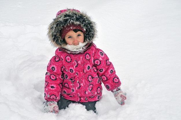 Belle fille enfant en bas âge jouant une journée d'hiver à l'extérieur avec de la neige.