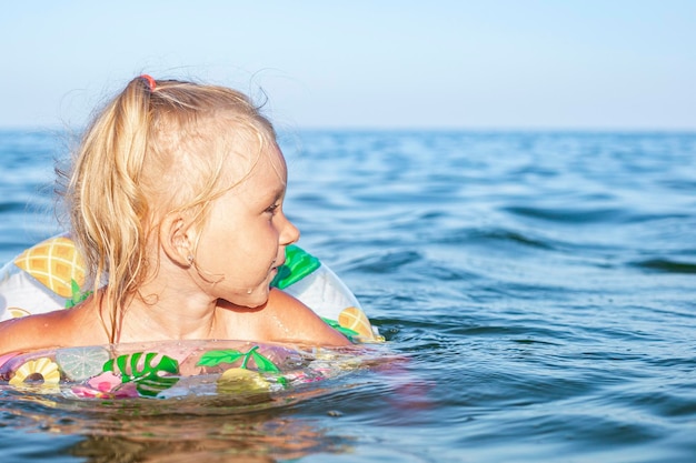 Belle fille enfant nage dans la mer avec un anneau gonflable.