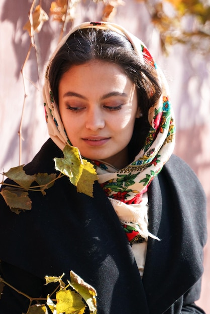 Une belle fille est assise dans le parc sur une balançoire, sur sa tête se trouve un foulard traditionnel russe. Portrait