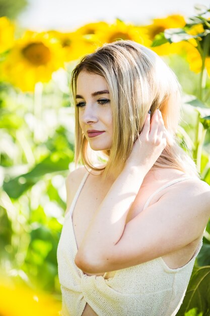 Belle fille européenne dans une robe blanche sur la nature avec des tournesols