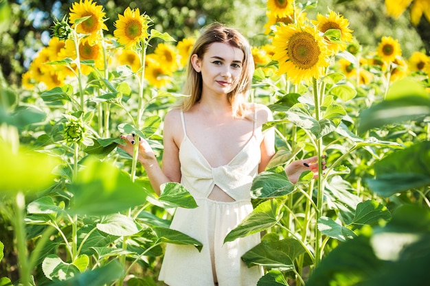Belle fille européenne dans une robe blanche sur la nature avec des tournesols