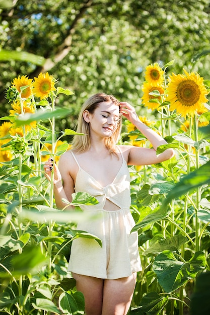 Belle fille européenne dans une robe blanche sur la nature avec des tournesols