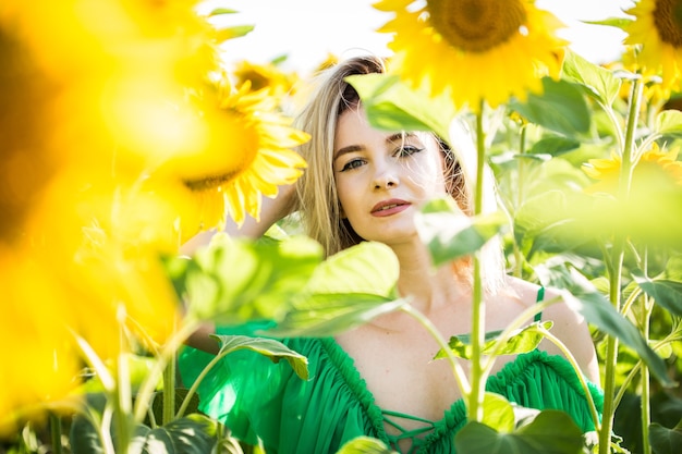 Belle fille européenne dans une robe verte sur la nature avec des tournesols