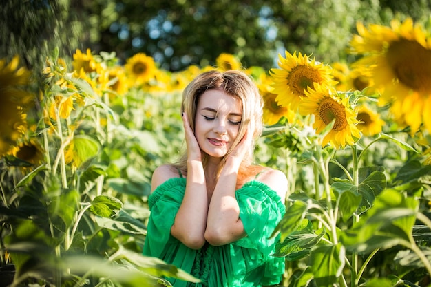 Belle fille européenne dans une robe verte sur la nature avec des tournesols