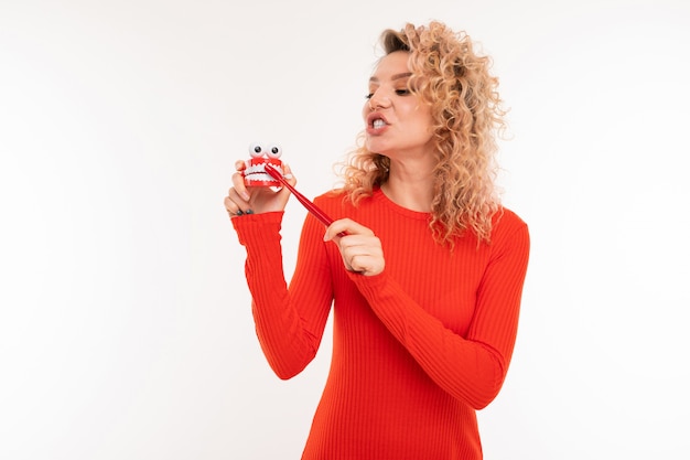 Belle fille européenne tient une brosse à dents dans les mains sur un blanc