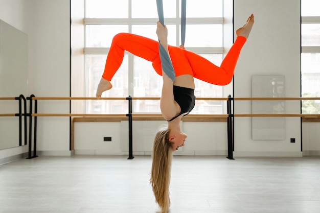 Belle fille faisant des étirements dans la salle de gym pour le yoga à la mouche