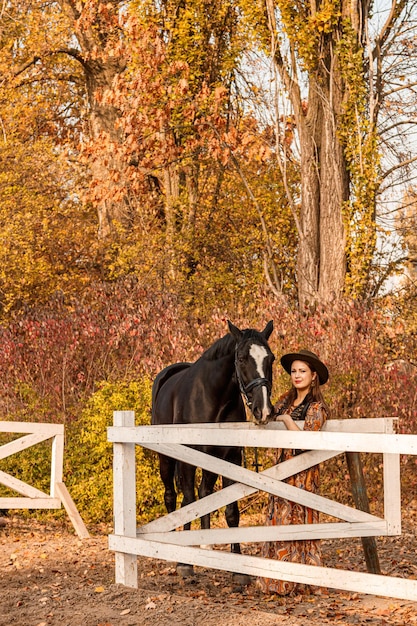 Belle fille une femme marche avec un cheval route d'automne