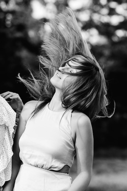 Une belle fille a fermé les yeux et remue ses cheveux sur la photographie en noir et blanc