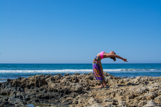 Photo la belle fille avec une figure sportive pratique le yoga en plein air près de la mer. été.